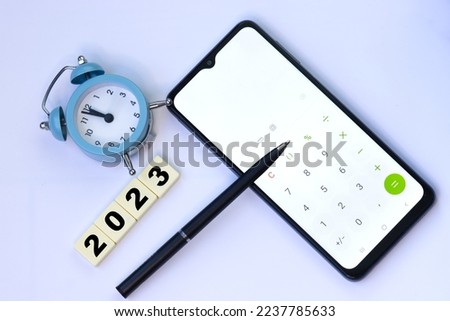 Concept for financial planning and reminder for 2023. Clock, pen and mobile phone calculator. Space for text on mobile..