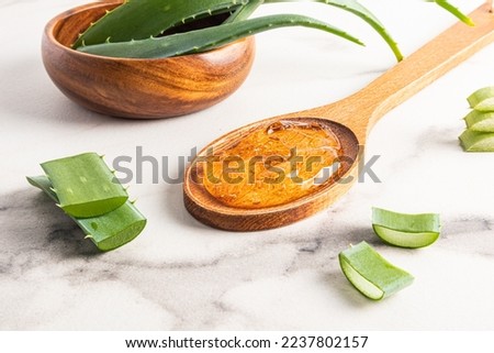Exstrate organic aloe vera gel in a wooden spoon on a marble white background. the leaves of the plant in the bowl. cosmetic self-care