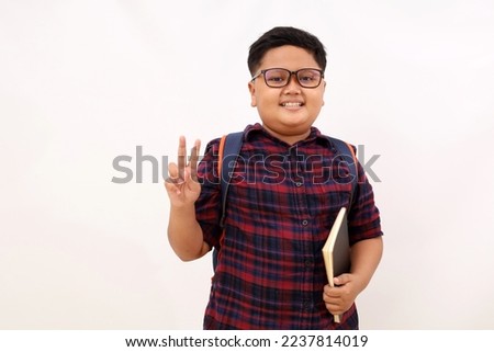 Happy asian school boy standing while showing two fingers. Isolated on white background
