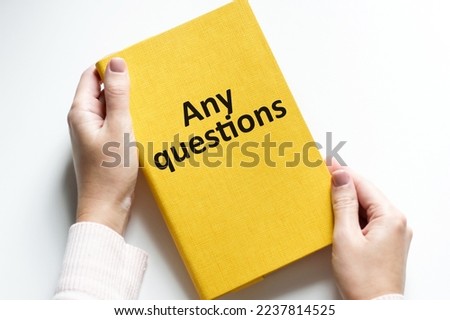 a man in the office holds a notebook with text ANY QUESTIONS. business concept