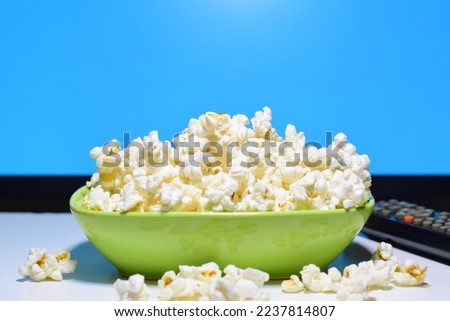 Popcorn in a green bowl, ready to eat while watching a movie. Front shot and copy space.
