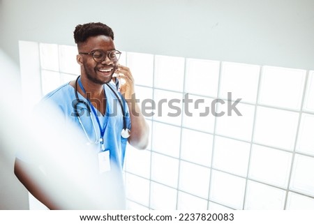 Portrait Of Male Nurse Wearing Scrubs In Exam Room. Portrait of male nurse with some medical record at hospital. A male nurse is at work at the hospital. He is wearing her scrubs and is smiling 