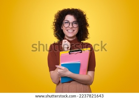 Portrait of a young entrepreneur woman making notes in a notebook smiling against a yellow background. People lifestyle concept. Creative concept idea. Creative