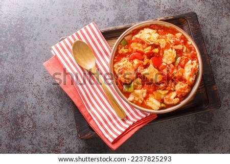 Cod stew with vegetables peppers, tomatoes, garlic and onions close-up in a bowl on the table. Horizontal top view from above
