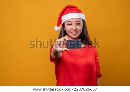Cute woman in red dress and santa holding a credit card in hand