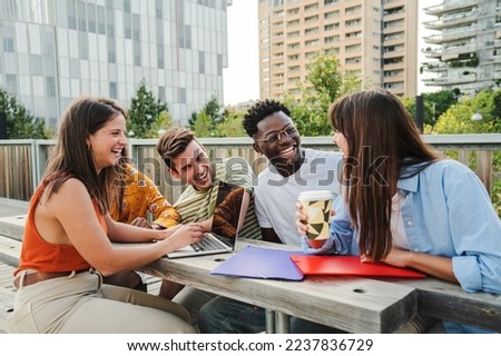 Multiracial smiling group of five teenagers students using laptop doing homework and enjoying a relaxed atmosphere outdoors at the university campus. Education concept. High quality photo