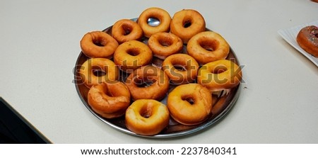 assorted donuts with chocolate frosted, pink glazed and sprinkles donuts. Donuts in hand or tray