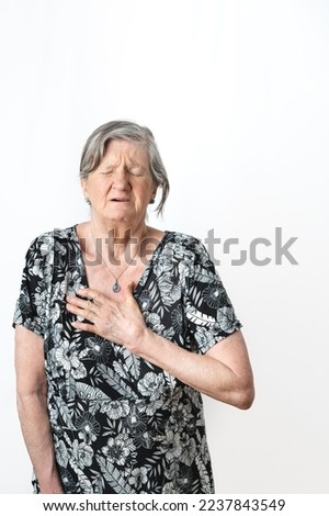 Old woman suffering heart pain and gesturing with eyes closed over isolated white background. Vertical photography