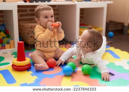 Two toddlers playing with toys sitting on floor at kindergarten Royalty-Free Stock Photo #2237846103