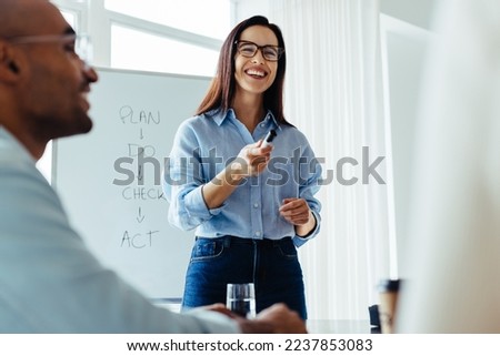 Happy business woman discussing ideas with her team during a meeting. Young business woman giving a presentation in an office.