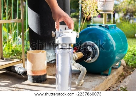 Water supply system from a well in a country house. New water filter. Hydraulic accumulator for storing water volume. Replacing a new water filter. Royalty-Free Stock Photo #2237860073