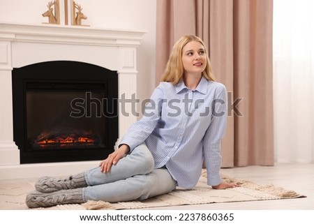Beautiful young woman resting near fireplace at home