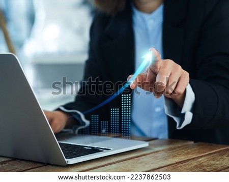 Investment technology, financial, return on investment - ROI concepts. Increasing arrow, the exponential curve of progress in business performance over charts on laptop draws by businesswoman's hand. Royalty-Free Stock Photo #2237862503