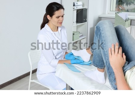 Beautiful female orthopedist fitting insole to patient's foot in hospital Royalty-Free Stock Photo #2237862909