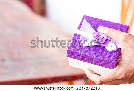 A set of gift boxes on men's hands from colored paper decorated with purple satin ribbon bows. happy holidays happy new year