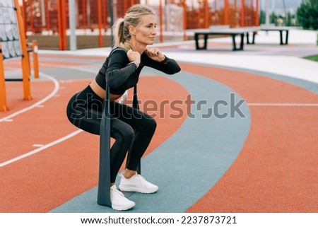 Young athletic woman is training on the sports ground using sports elastic bands. Royalty-Free Stock Photo #2237873721