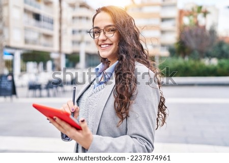Young hispanic woman executive using touchpad standing at street