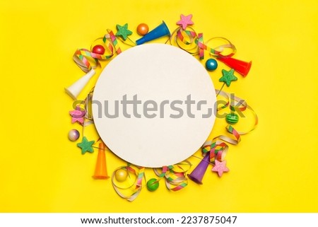 Greeting card with colored serpentines and whistles on a yellow background with round space for copywritter