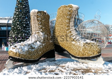 The composition is a huge golden skates covered with snow against the backdrop of a Christmas tree. The concept of winter and winter sports games.