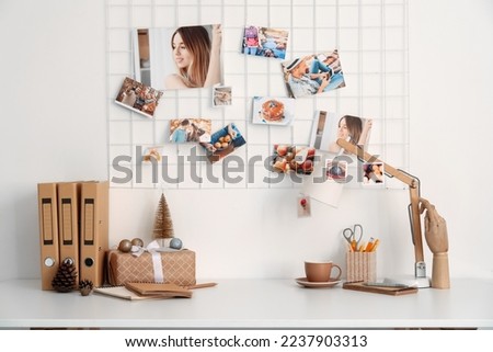 Christmas gift with folders and cup on table near light wall