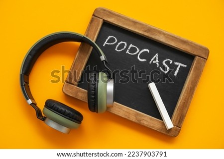 Chalkboard with word PODCAST and headphones on orange background