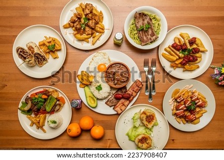 A still life with dishes of Peruvian and Ecuadorian gastronomy, chorizo with fried potatoes, a combined plate with rice and avocado, lomo saltado, fillet with green noodles, stuffed potato Royalty-Free Stock Photo #2237908407