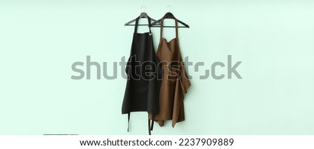 Clean aprons hanging on light blue wall