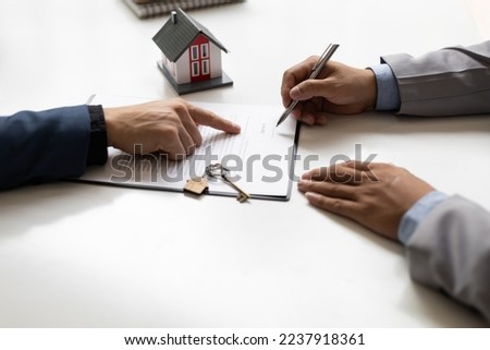 Businessmen and real estate agents sign contracts to legally sell homes.