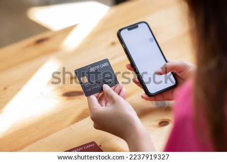 Close up back view of woman shopping online on smartphone using credit card woman paying with device pay bills on the web online banking Royalty-Free Stock Photo #2237919327