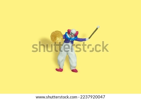 Miniature people toy figure photography. Full body of a bald clown holding crash cymbal and stick. Isolate on yellow background. Image photo