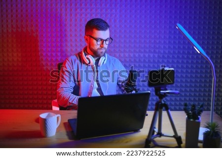 A video blogger records content in his studio. The backstage photo was taken from behind one of the participants in the shooting, at the beginning of the shooting when the blogger is preparing