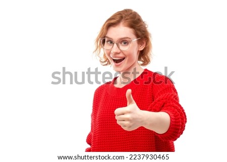 Young redhead woman shows hand with thumbs up and smiles at the camera isolated on white background
