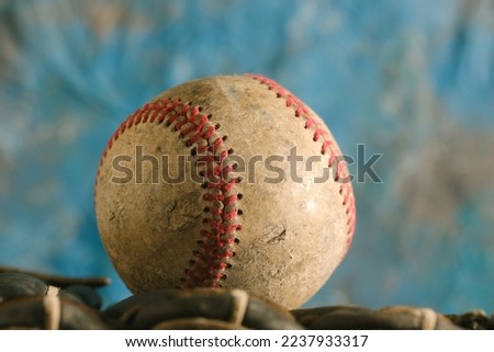 Baseball ball with old used texture closeup for sports equipment with blue blurred background.