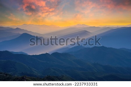 Golden light rays shining down to mountains. Sun rays over valley. Sun rays over hill. Beam of light from clouds on the mountains. oblique rays of sunlight through the mountains. Doi Pui Co, Thailand. Royalty-Free Stock Photo #2237933331