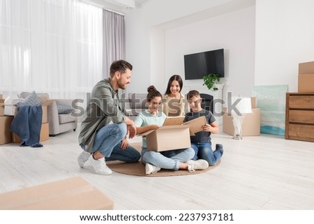 Happy family settling into new house and unpacking boxes on floor. Moving day