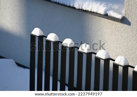 a metal fence with piles of snow above each post