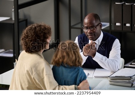 High angle portrait of young mother with child talking to caring black social worker in office Royalty-Free Stock Photo #2237954409