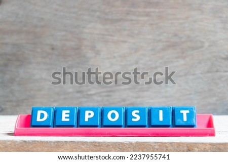 Tile alphabet letter with word deposit in red color rack on wood background