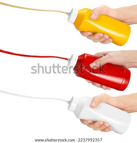 Set of hands squeezing mustard, ketchup and mayonnaise out of plastic bottles, isolated on white background Royalty-Free Stock Photo #2237992357