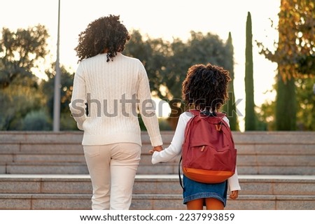 Happy African American mother and daughter preschool student walking to school. Beginning of lessons. First day of fall. Parenthood or love and bonding expression concept. Royalty-Free Stock Photo #2237993859