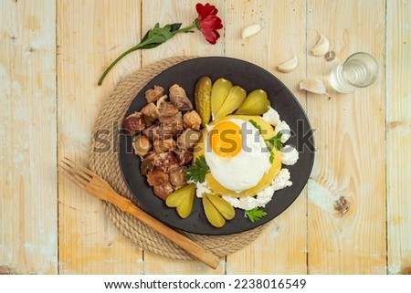 Romanian traditional dish  "Tochitura moldoveneasca", Recipe made with pork meat and sausages, Cheese, egg and " mamaliga", flat lay close up, on a black plate
