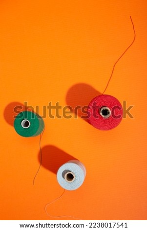 Three coils with colored threads on a colored background Royalty-Free Stock Photo #2238017541