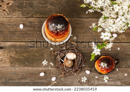 Traditional Easter cake in a rustic style. Vintage baking pot, blooming cherry plum branches. Old wooden background, greeting card