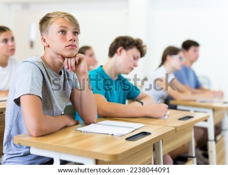 Teenager students sitting at desks and listening. Boy sitting in foreground. Royalty-Free Stock Photo #2238044091