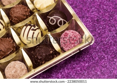 Golden box with delicious chocolate candies on purple table