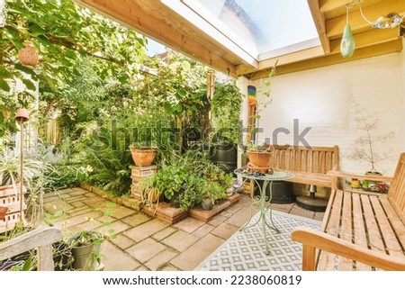 a patio with lots of plants and pots on the ground in front of a white brick wall that has been painted yellow