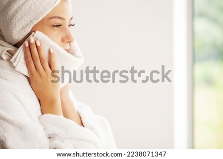 Young woman wiping her face with white towel after waking up in the morning Royalty-Free Stock Photo #2238071347