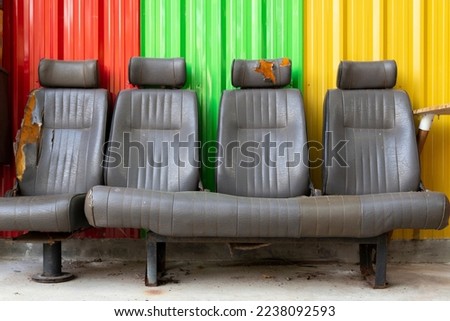 The seats of an old carriage have been converted into chairs inside a building with a colorful galvanized backdrop.