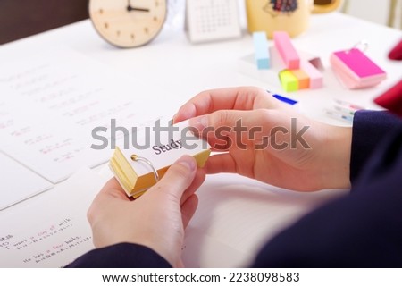 A Japanese woman in a uniform who learns words in an English memorization book.

The notes are written in English and their translations in Japanese. Royalty-Free Stock Photo #2238098583