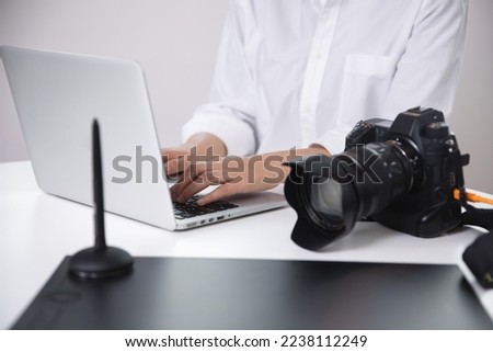 Female photographer, blogger reviewing photos taken with her camera using a laptop